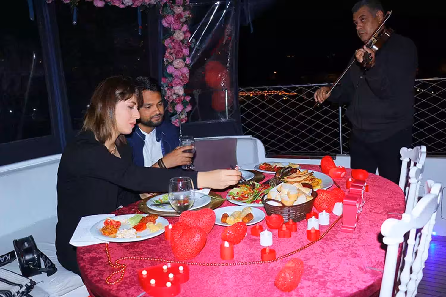 Romantic yacht dinner proposal setup with candles, heart decor and live violinist for a private cruise night