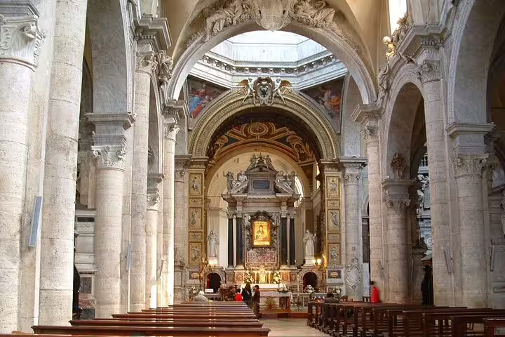 Baroque church interior in Rome with ornate altar, marble arches and pews on a Caravaggio masterpieces private tour
