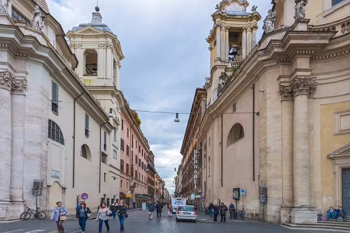 Visitors stroll between Baroque churches on a historic Rome street explored on a Caravaggio and Baroque masterpieces private tour