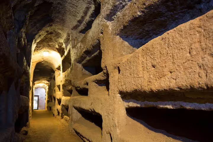 Long corridor of early Christian catacombs with carved burial niches on Rome in 2 Days Colosseum and Vatican tour