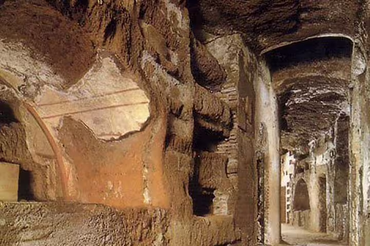 Ancient tunnels of the Rome catacombs with carved burial niches featured on a 2 day Colosseum and Vatican tour