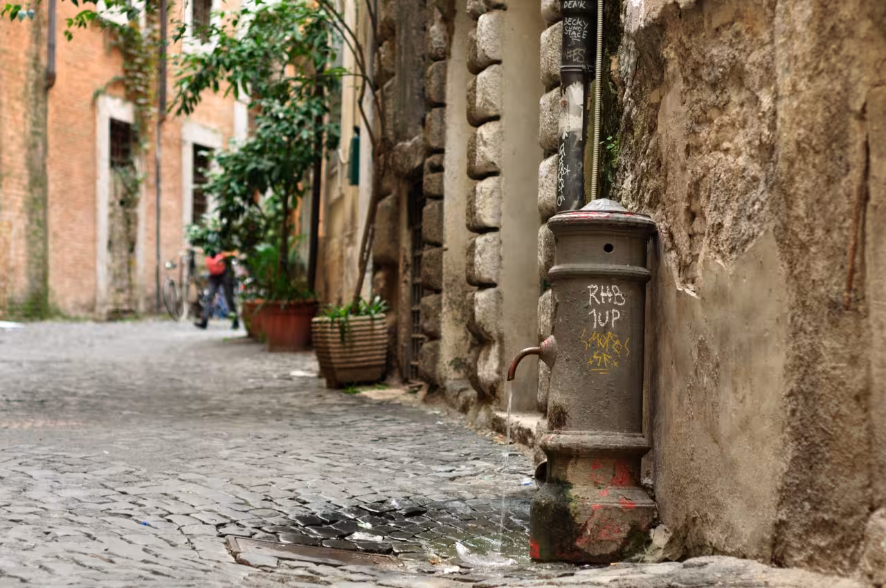 Cobblestone Rome alley with a vintage water fountain, atmospheric scene on a Rome Ancient Amusement tour