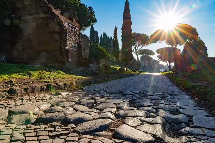 Sunrise over the historic Appian Way cobblestones near the Colosseum, included in Rome catacombs and underground tours with transfer
