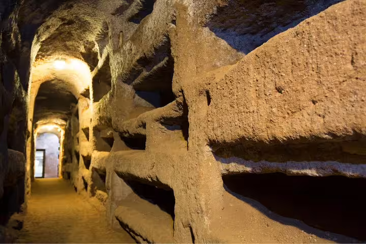 Dimly lit ancient Christian catacombs tunnel in Rome explored on a Colosseum and underground tour with transport included