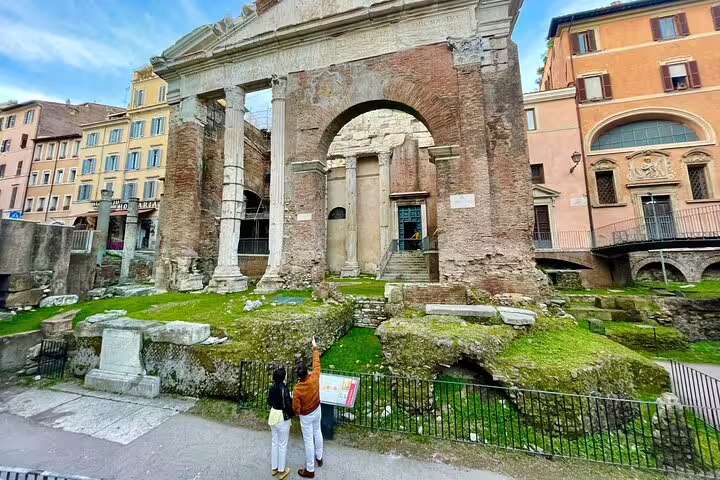 Couple on a guided walking tour admiring ancient Roman arch ruins and temples in central Rome’s historic city center