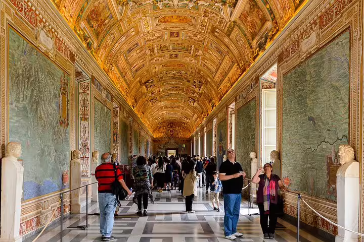 Guided group walking through the ornate Gallery of Maps in the Vatican Museums on a Rome Colosseum and Vatican fast track tour