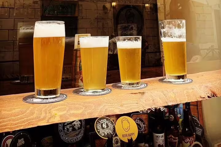 Four craft beers on a rustic wooden bar at a Vatican brewery, perfect for a private tour with a local foodie guide.