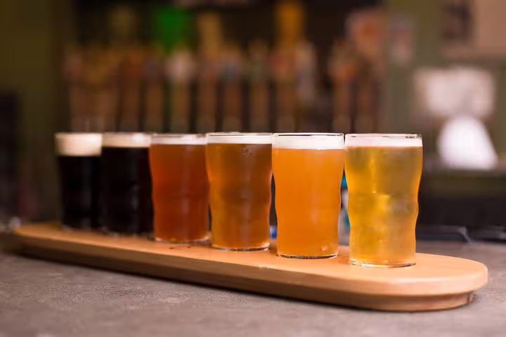 A selection of craft beers in varying colors on a tasting board, featured in the Vatican's Craft Beer Private Tour with a local foodie.