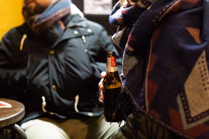 Close-up of a person holding a craft beer bottle during a cozy night on the Private Rome Walking Tour.