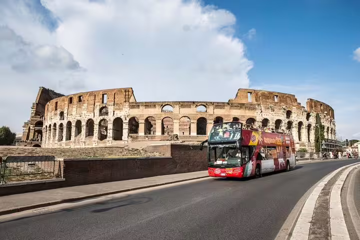 Rome private double decker open bus panoramic guided tour passing the Colosseum on a sunny day with skip-the-line sightseeing