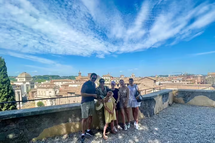 Family enjoying a kids friendly private guided tour in Rome, overlooking historic rooftops and domes under a bright summer sky