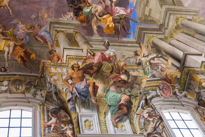 Ornate frescoes adorn the ceiling of a historic Rome site, showcasing vibrant Renaissance art on a tour of iconic landmarks.
