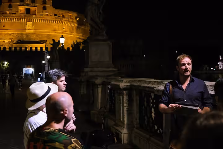 Tour guide narrating eerie stories to a group near Castel Sant'Angelo during Rome's Dark Side Ghost Tour.