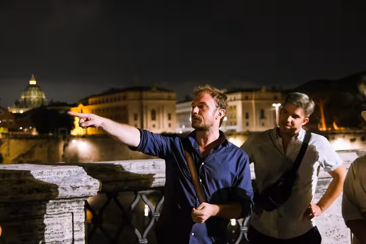 Guide points out haunted sites on Rome's night tour, sharing ghost stories and legends under the city lights.