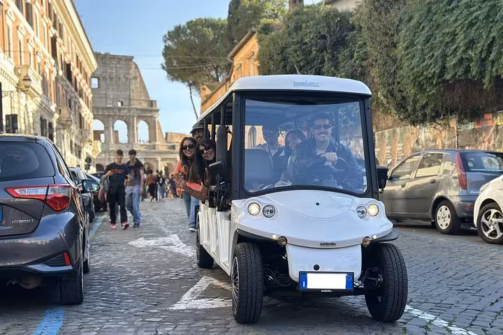Golf cart tour in Rome with tourists enjoying views of the Colosseum on a sunny day with local guide.