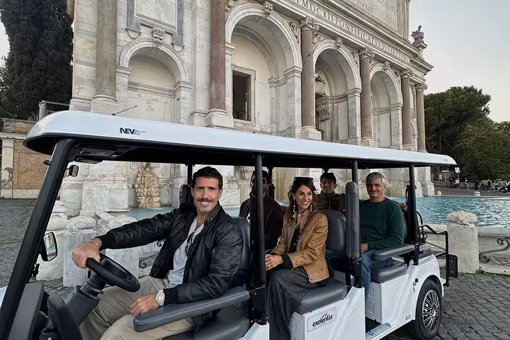 Group on a golf cart tour in front of Rome's historic Fontana dell'Acqua Paola with a local guide.
