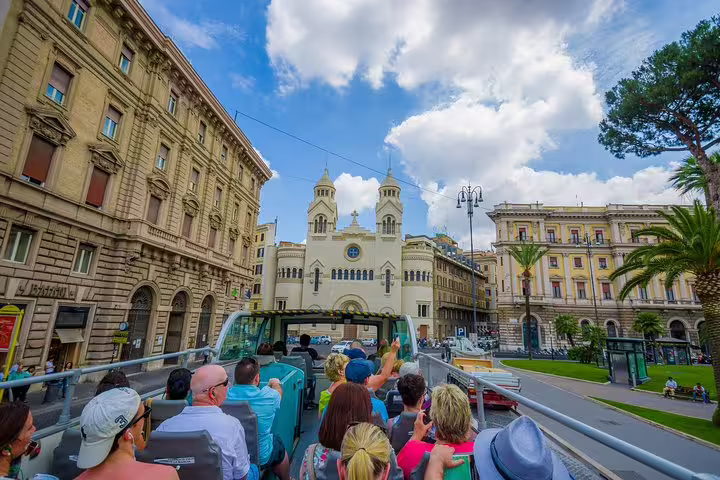 Open-top hop on hop off sightseeing bus in central Rome passing historic palaces en route to Vatican Museums tour