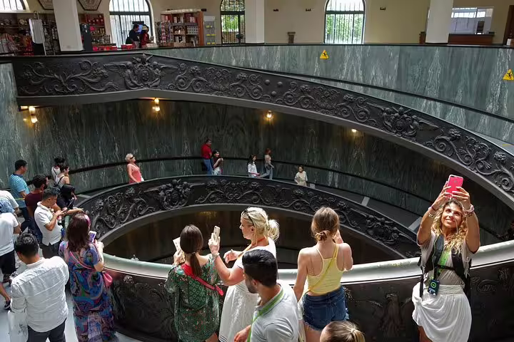 Visitors taking photos on the famous spiral staircase inside the Vatican Museums during a Rome hop on hop off guided tour