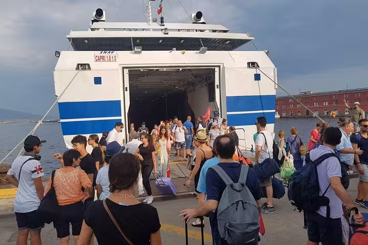 Passengers boarding ferry at Naples Beverello pier after Rome or Fiumicino airport transfer, luggage in hand