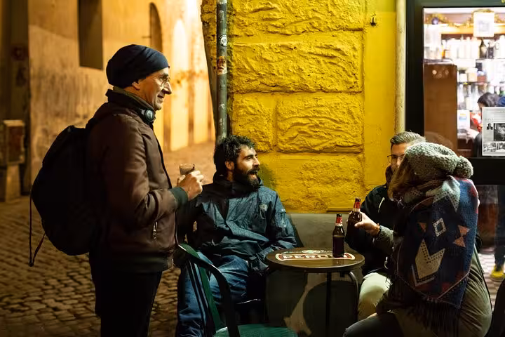 Visitors engage in conversation while enjoying craft beers at an outdoor stop on the Rome night tour.