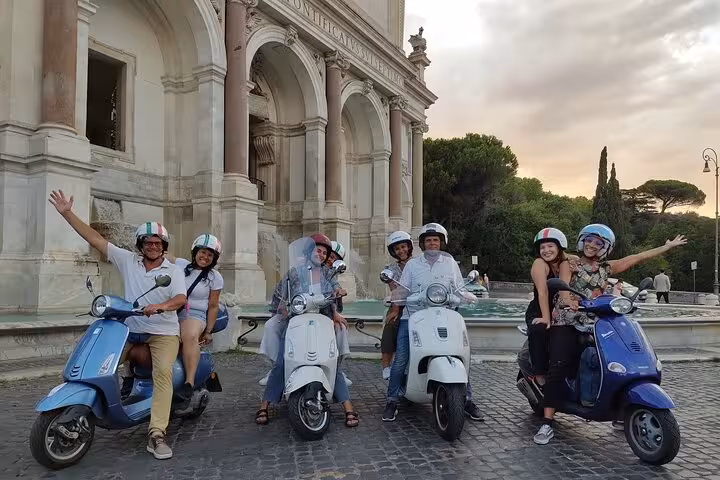 Group of friends on Vespas enjoy scenic Rome night tour, stopping at iconic landmarks for a memorable experience.