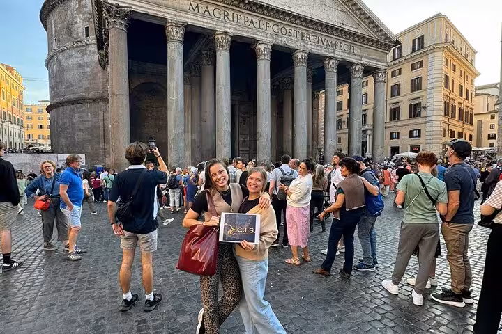 Visitors enjoy the grandeur of Rome's Pantheon entrance, capturing memories with a digital audio guide for an enriching tour.
