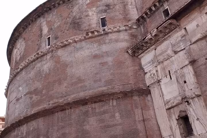 Exterior view of the ancient Pantheon in Rome, showcasing its iconic circular brickwork and historic architecture.