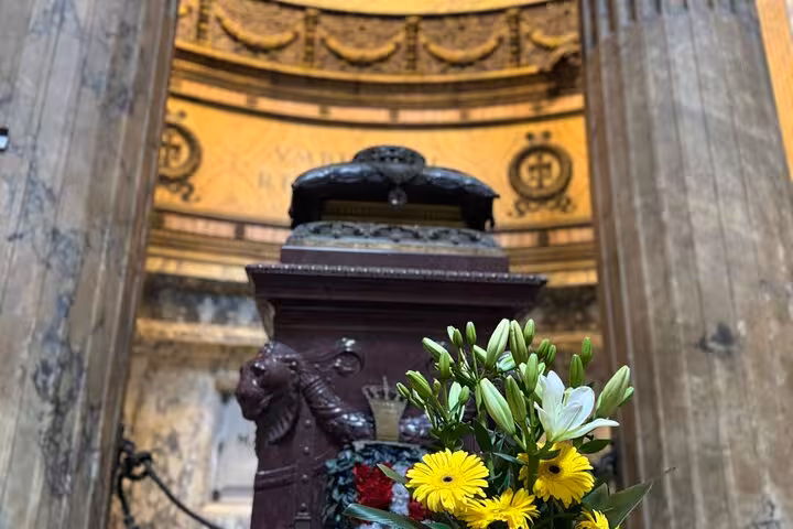 Close-up of vibrant flowers inside Rome's Pantheon, with intricate marble interiors reflecting its historic grandeur.