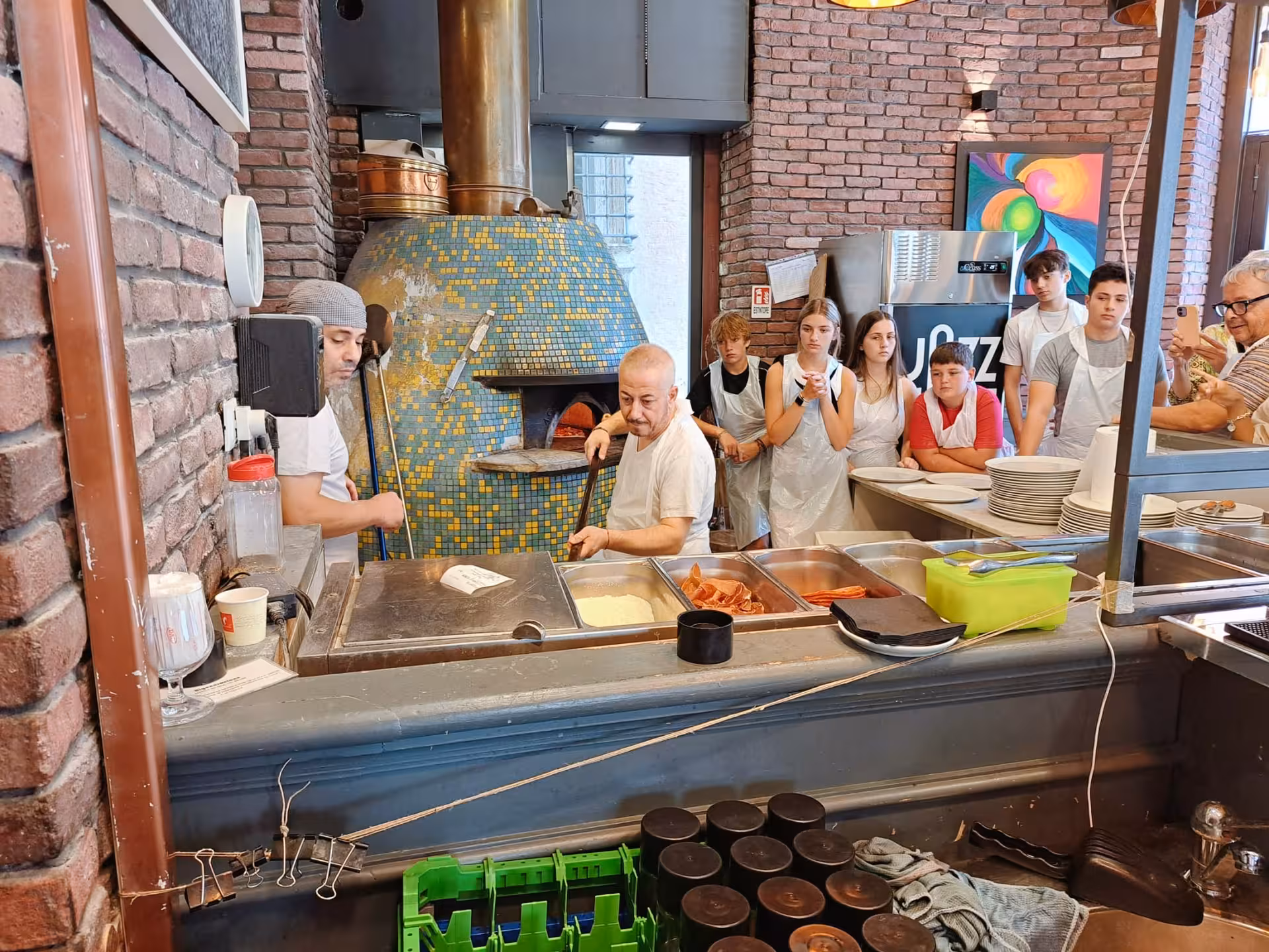 Participants watch a skilled chef prepare pizza in a traditional wood-fired oven at Jazz Cafe in Rome.