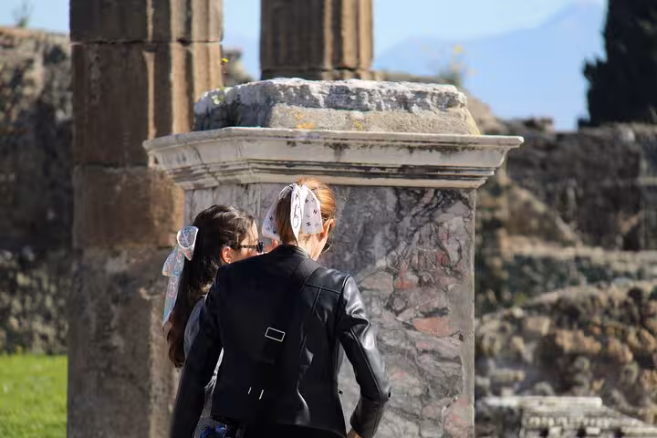 Tourists exploring ancient stone ruins in Pompeii, capturing the historical essence on a guided tour from Rome.