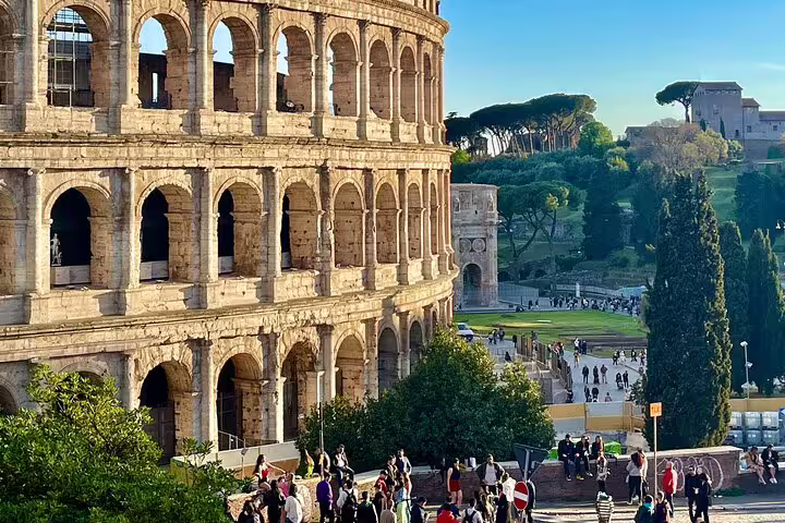 Guided Rome private panoramic tour near the Colosseum with crowds exploring ancient ruins and green gardens at golden hour
