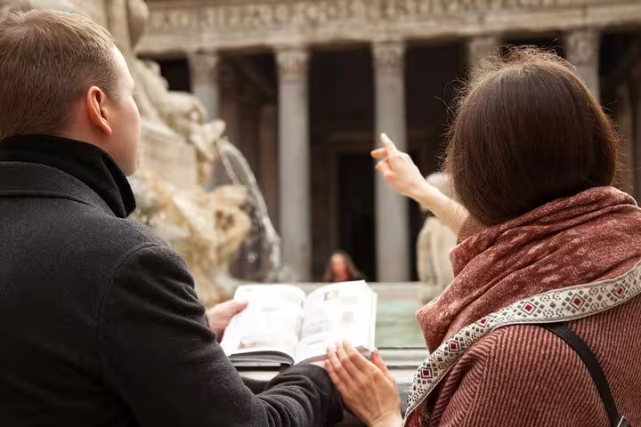 Tourists explore ancient Roman architecture with a guidebook during a private walking tour, highlighting Rome's hidden gems.