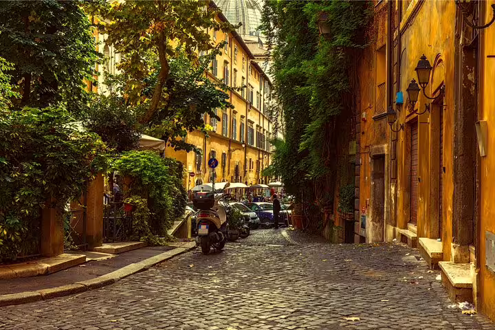 Charming cobblestone street in Rome with vibrant buildings and lush greenery, perfect for a private city highlights tour for newcomers.