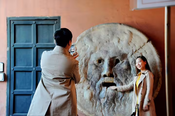 Tourists enjoy the iconic Mouth of Truth during a Private Rome Kickstart Tour, capturing memorable moments and city highlights.