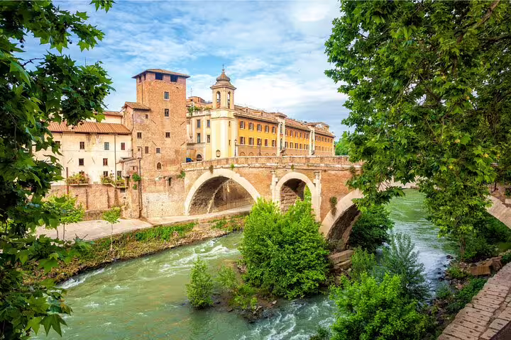 Scenic view of Rome's historic Ponte Cestio and lush greenery along the Tiber River, perfect for a private city highlights tour.