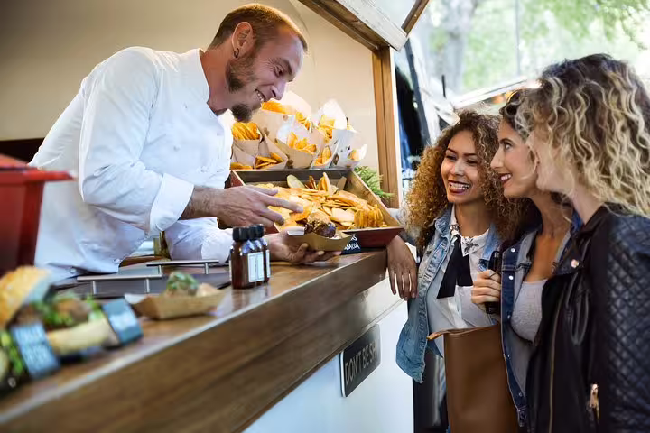 Tourists enjoy local street food from a smiling vendor during a private walking tour of Rome's hidden culinary gems.