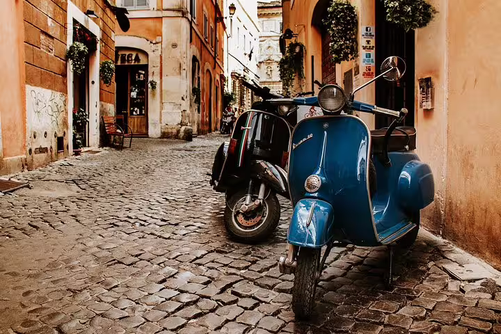 Vintage scooters parked on a charming cobblestone street in Rome, perfect for exploring city highlights on a private kickstart tour.