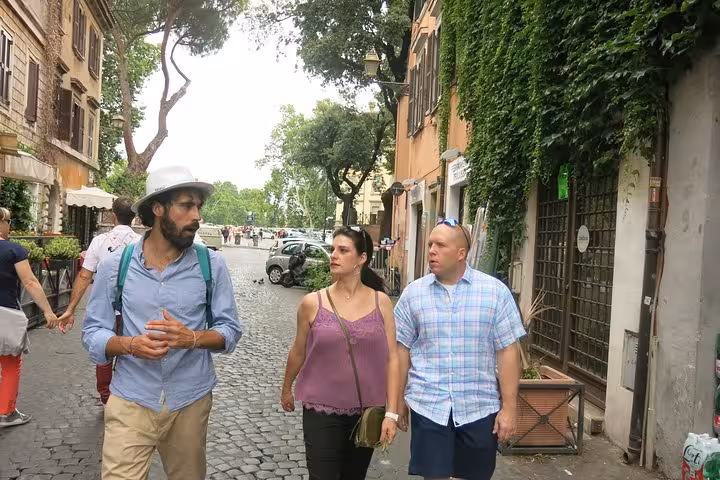 Tourists exploring the charming cobblestone streets of Rome's Rione Parione district on a private walking food tour.