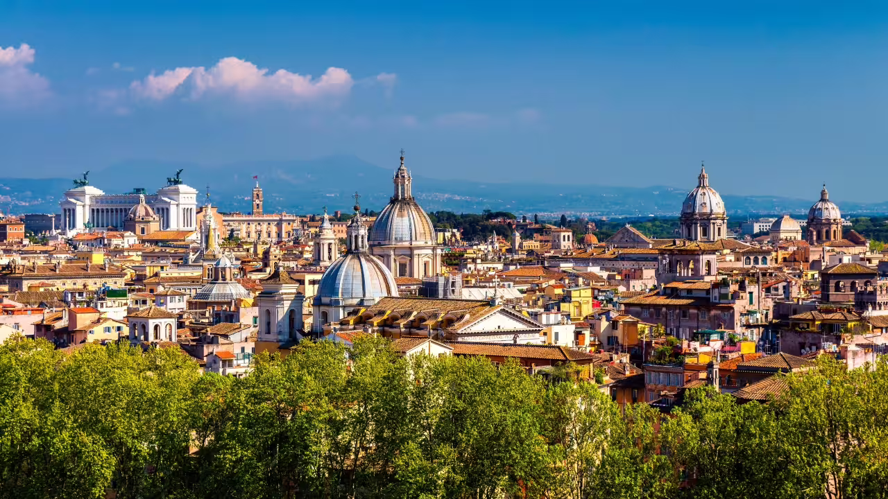 Panoramic view of Rome's iconic skyline featuring domes and historic architecture under a clear blue sky.