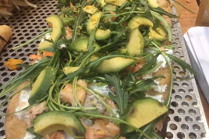 Fresh Italian flatbread topped with avocado and arugula, featured in a Rome Testaccio food tour.