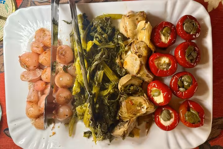 Colorful antipasti platter with marinated onions, greens, artichokes and stuffed peppers served on a Rome Trastevere food tour