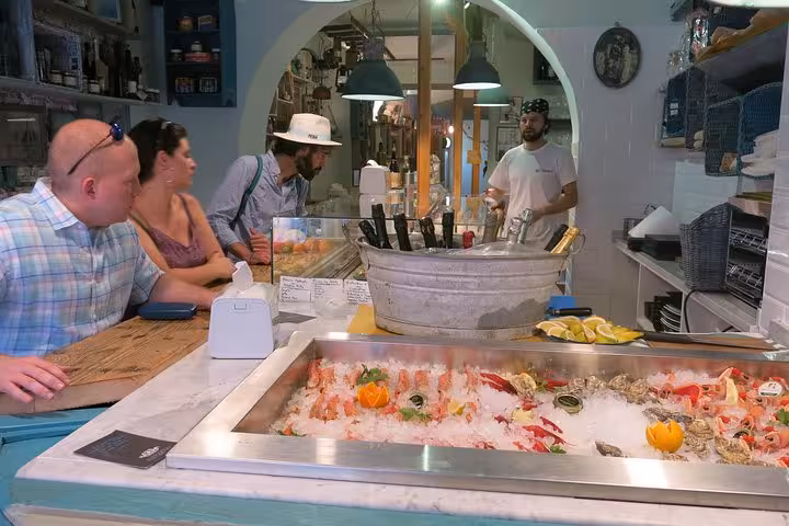 Tour participants engage with a local vendor at a seafood bar in Trastevere, Rome, during a culinary adventure.