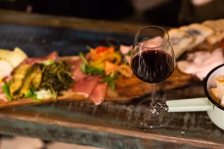 Delight in a glass of red wine paired with a rustic charcuterie board on the Rome Trastevere food walking tour.