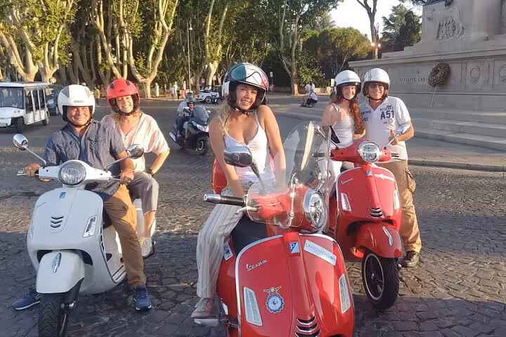 Smiling tourists on Vespas gather near a Rome monument during a private guided tour in the city.