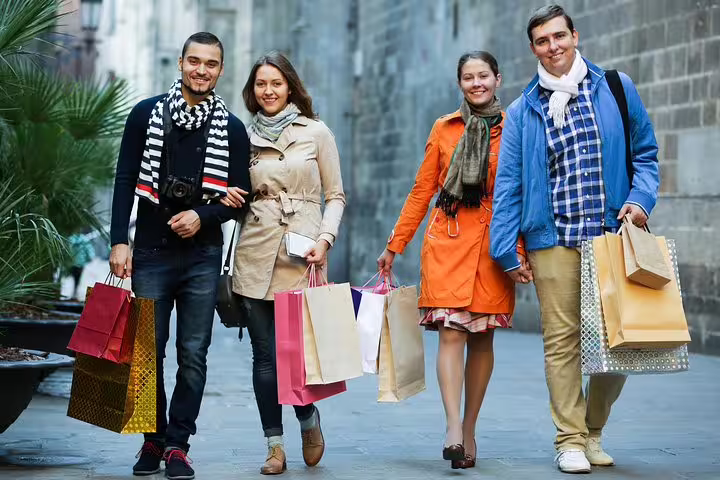 Group of friends carrying colorful shopping bags while strolling Rome’s historic streets on a VIP fashion tour