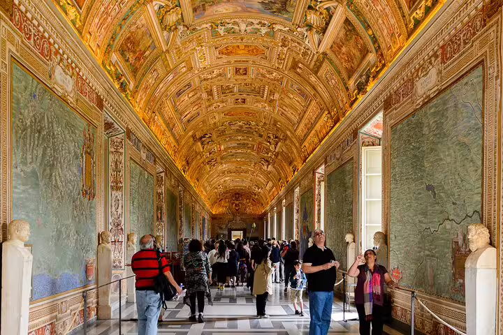 Visitors on a Rome private VIP tour walking through the ornate Gallery of Maps inside the Vatican Museums