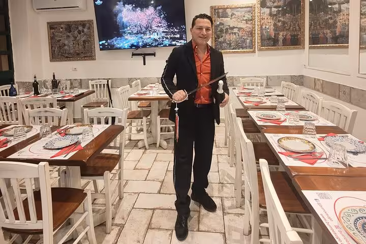 Host in an elegant Roman restaurant setting up for a wine and food pairing event, surrounded by neatly set tables.