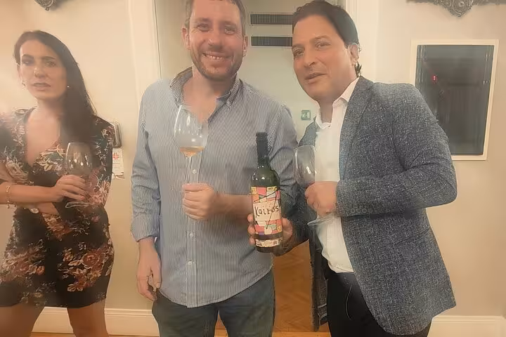 Two men and a woman enjoying wine at Rome mini sommelier course, showcasing bottle and glasses.