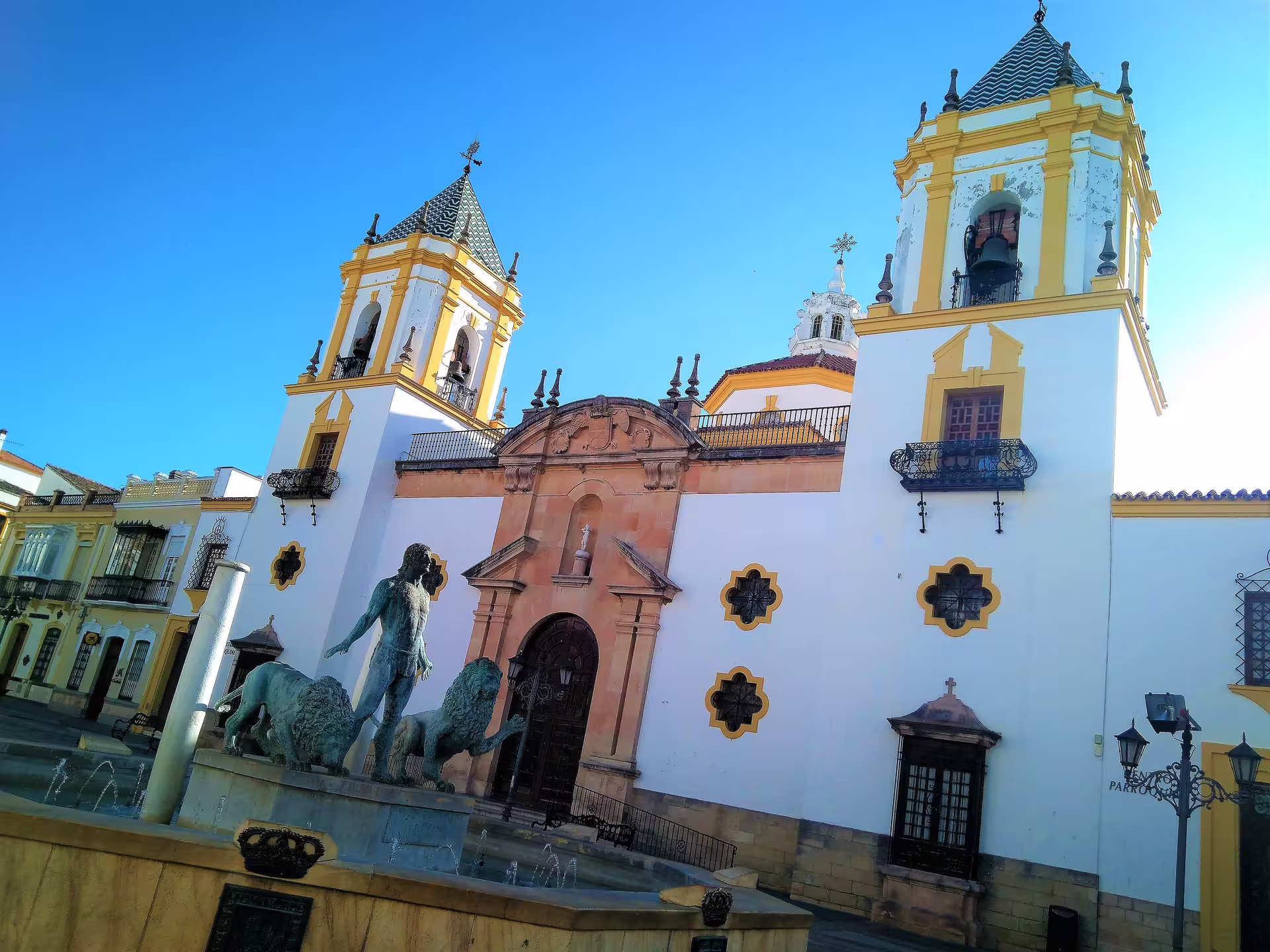 Ronda church and plaza with fountain under blue sky, stop on Ronda and Setenil de las Bodegas tour from Malaga