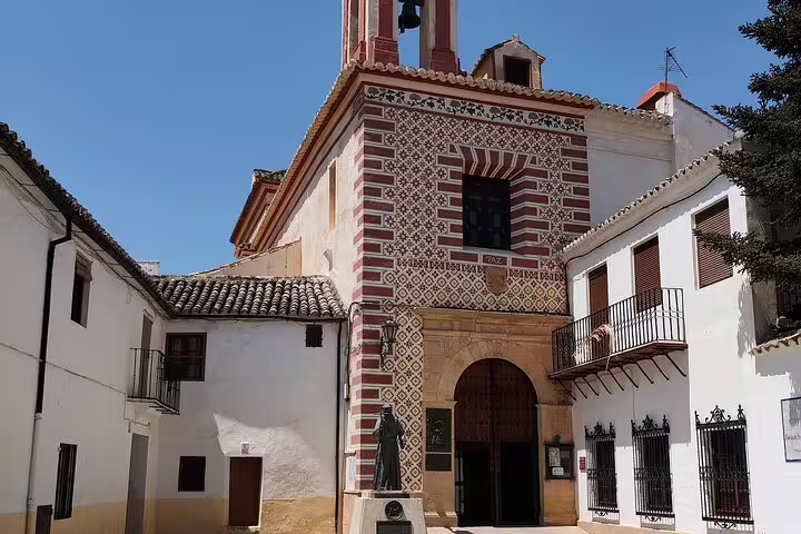Charming historic building in Ronda with intricate brickwork and a statue, under a clear blue sky.